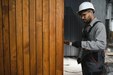 İnşaat atölyesindeki prefabrik modüler ev için ahşap döşemeleri cilalayan odaklı marangoz.