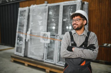 Bir inşaat atölyesinde çalışan Arap işçiler, koruyucu giysiler giyiyorlar, modüler ev parçalarının önünde güvenle duruyorlar, montaja hazırlar.