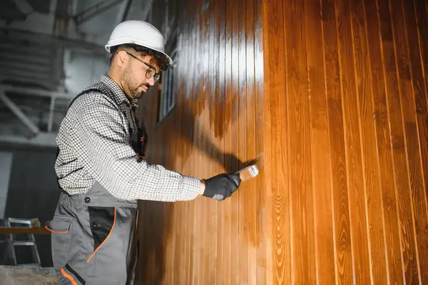Modüler ev inşaat atölyesinde prefabrik ahşap duvar bölümünü cilalayan odaklanmış marangoz.