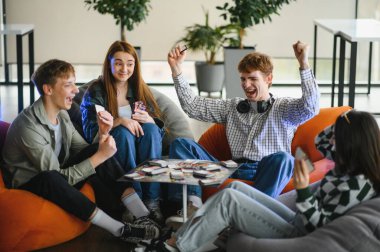 Dört neşeli genç armut koltukta oturup masa oyunu oynuyor ve birlikte eğleniyorlar.