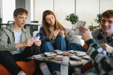İş arkadaşları, modern ofis ortamında bir kart oyununun keyfini çıkarıyorlar, dostluğu ve rahatlığı teşvik ediyorlar.