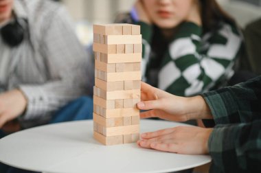 Dostlar, evlerinde blok yığma oyununun keyfini çıkarıyorlar. Gülüyor ve konsantre oluyorlar. Tahta bloklardan oluşan tehlikeli bir kule inşa ediyorlar.