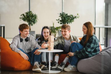 Dört neşeli arkadaş armut koltuklarda oturup birlikte büyüleyici bir tahta kule oyunu oynayarak boş zamanlarının tadını çıkarıyorlar.