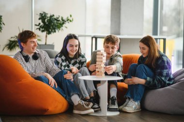 Dört neşeli arkadaş rahat armut koltuklarda oturup büyüleyici bir masa oyunu oynuyor ve birlikte vakit geçiriyorlar.