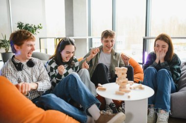 Dört genç puf minderlerinde oturuyor, tezahürat yapıyor ve gülüyorlar. Bir blok dizme oyunu oynarken, birlikte boş zamanlarının keyfini çıkarıyorlar.