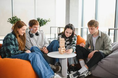 Dört genç arkadaş rahat armut koltuklarda oturup büyüleyici bir masa oyunu oynuyorlar.