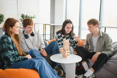 Bir grup arkadaş sıcak bir oturma odasında jenga oynayarak eğleniyor, arkadaşlığın tadını çıkarıyor ve neşeli anılar yaratıyorlar.