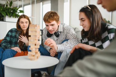 Genç yetişkinlerden oluşan bir grup rahat bir oturma odasında bloklama oyunu oynuyorlar. Birlikte yarışırken arkadaşlığı ve heyecanı teşvik ediyorlar.