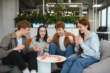 Dört arkadaş heyecanla bir masa oyunu oynuyor, kahkahalar ve heyecanları paylaşıyorlar. Samimi ortam onların neşeli bağlanma deneyimini arttırır.