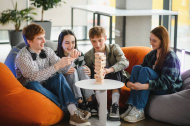 Dört arkadaş boş zamanın tadını çıkarıyorlar, büyüleyici bir masa oyunu oynuyorlar ve modern ortamdaki rahat armut koltuklarda dinleniyorlar.