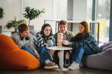 Dört genç, puf minderlerinde oturup oyun oynuyorlar, boş zamanlarının tadını çıkarıyorlar.