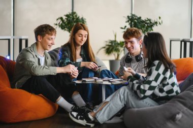 Dört meslektaş rahat bir ofis alanında masa oyunu molası vererek takım çalışmasını ve arkadaşlığı teşvik ediyor.