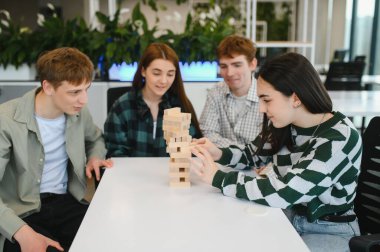 Bir grup genç iş arkadaşı modern ofis dinlenme odasında ahşap bloklarla oynayıp boş zamanlarının tadını çıkarıyorlar.