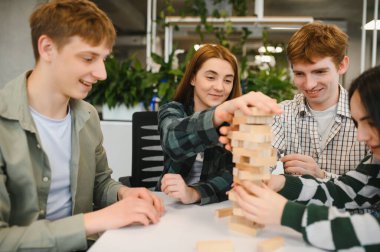 Dört meslektaşı ofis molasında Jenga oynuyorlar. Klasik bir blok dizme oyunu. Takım çalışmasını ve dostça rekabeti destekliyorlar.