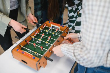 Mola sırasında arkadaşça bir masa futbolunun keyfini çıkaran neşeli meslektaşlar, takım çalışması ve dostluk sergiliyorlar.