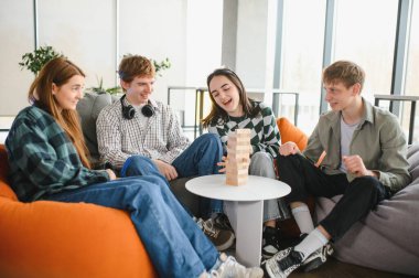 Dört neşeli arkadaş puf minderlerinde oturmuş Jenga oynuyorlar.