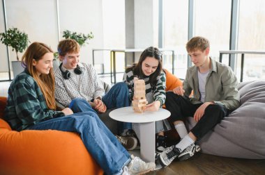 Bir grup genç iş arkadaşı, hareketli ve çağdaş ofis ortamında büyüleyici bir masa oyunu oynuyorlar.