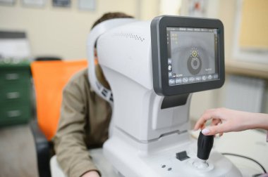 Doktor, modern oftalmoloji kliniğinde doğru teşhis ve kişiselleştirilmiş tedavi sağlayarak hastanın görüşünü incelemek için otomatik fraktometre kullanıyor.