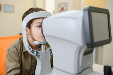 Göz doktorunun muayenesi sırasında görme tanısı için otomatik fraktör kullanan çocuk hasta