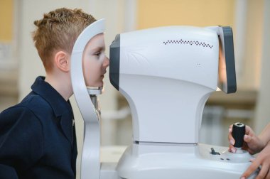 Oftalmolog, klinik bir ortamda bir çocuğun görme yetisini kontrol ediyor. Görme ve bakımını sağlama alıyor.