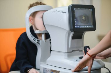 Göz fraktörü ile göz muayenesinden geçen çocuk göz hekimliği ve görme bozukluklarını kontrol ediyor.