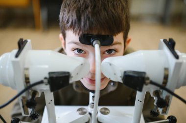 Çocuk hasta görme yeteneğini bir sinnoptofor kullanarak kontrol ettiriyor. Strabismus ve amblyopia tanısı ve tedavisi için bir cihaz.