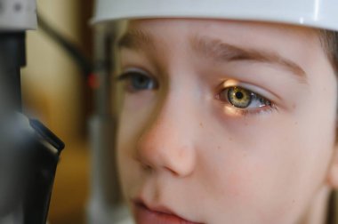 Optalmoloji kliniğinde gelişmiş ekipman kullanılarak vizyon teşhisi konan çocuk, potansiyel göz sorunlarının doğru değerlendirilmesi ve tedavisinin sağlanması
