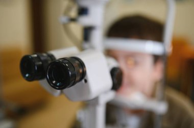 Bir göz hastalıkları kliniğinde genç bir çocuğun görme yetisini inceleyen tıbbi ekipmanların yakın çekimi, görme ve tedavi