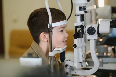 Görme yeteneğini fosforopter kullanarak kontrol ettiren çocuk modern bir göz hastalıkları kliniğinde profesyonel göz bakımı görüyor.