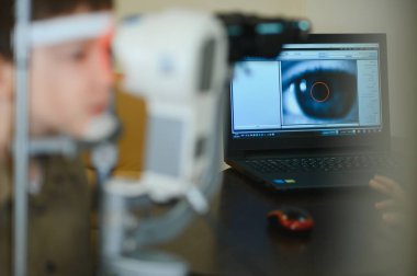 Göz muayenesinden geçen bir çocuk, göz hekimliği kliniğinde ileri seviye tanı ekipmanları kullanılarak, çocuklar için modern görüş bakımı sunuluyor.