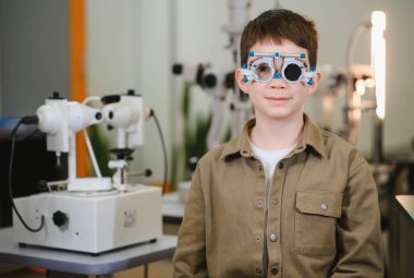 Bir göz doktorunun muayenehanesinde göz muayenesi yapılırken, vizyon değerlendirmesi ve bakıma odaklanan bir çocuk.