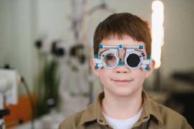 Bir göz doktorunun muayenehanesinde göz muayenesi sırasında, vizyonu ve göz sağlığını değerlendiren bir çocuk.