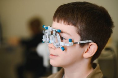 Bir göz doktorunun muayenehanesinde göz muayenesinden geçen çocuk, görüş değerlendirmesi ve bakıma odaklanıyor.