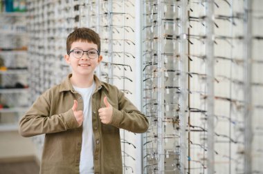 Yeni gözlük takan gülümseyen çocuk göz doktoru dükkanında iyi bir bakış açısı ve yeni gözlüklerden memnun.