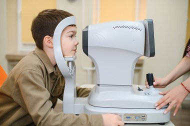 Oftalmolog, son teknoloji klinik ortamında otomatik fraktör kullanan bir çocuk üzerinde görüş kontrolü yapıyor.