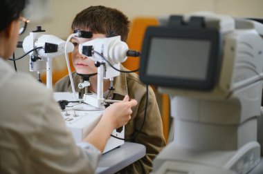 Klinikte oftalmolog tarafından işletilen yenilikçi ekipmanlarla vizyon teşhisi konan çocuk