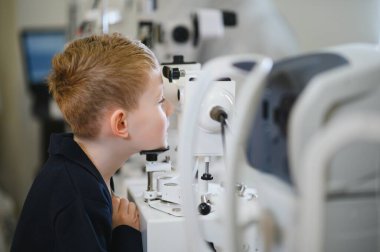 Modern bir klinikte göz muayenesi sırasında tıbbi ekipman kullanan çocuk, özel bir göz bakımı görmektedir.