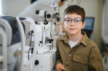Modern bir göz kliniğinde yapılan göz muayenesi sırasında gözlük takan genç bir çocuk sağlıklı bir görüş sağlıyor.