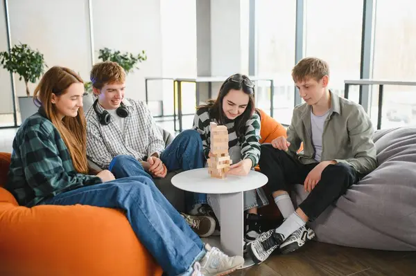 Bir grup genç iş arkadaşı, hareketli ve çağdaş ofis ortamında büyüleyici bir masa oyunu oynuyorlar.