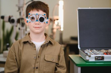 Bir göz doktorunun kliniğinde göz muayenesinden geçen ve vizyon ve göz sağlığını değerlendirmeye odaklanan bir çocuk.