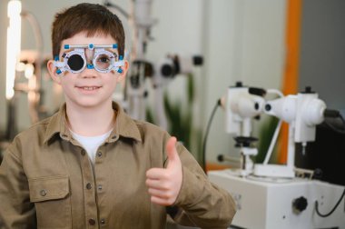 Göz muayenesi sırasında göz doktorunun ofisinde başparmak ameliyatı yapan çocuk.