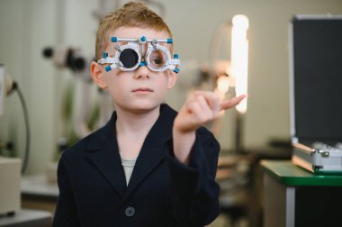 Klinikte yapılan göz muayenesi sırasında üzerinde deneme çerçevesi olan çocuk görme keskinliğini kontrol ediyor.