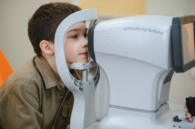 Görme yeteneğini kontrol ettiren bir çocuk göz hekimliği kliniğinde modern bir otomatik fraktör kullanarak doğru teşhis ve tedavi sağlıyordu.