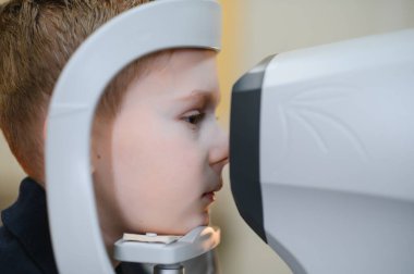 Görme yeteneğini kontrol ettiren bir göz doktoru modern bir oto-fraktör kullanıyor.