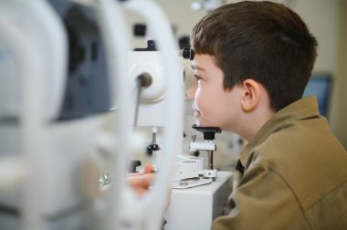 Genç bir çocuğun modern bir klinikte fosfor kullanan bir göz doktoru tarafından gözleri kontrol ediliyor.
