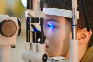 Çocuk, modern bir klinikte uzman bir göz doktoruyla vizyon teşhisine tabi tutuluyor.
