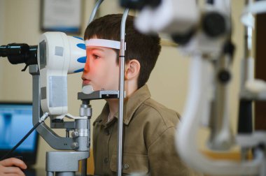 Görme yeteneğini göz doktoru tarafından kontrol ettiren bir çocuk. Görme ve tedavi konusunda uzman.