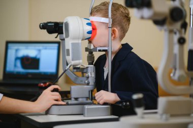 Göz muayenesinden geçen genç bir çocuk modern ekipmanlarla klinikte göz doktoru tarafından ameliyat ediliyor.