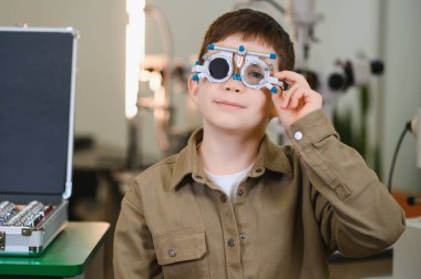 Göz muayenesi sırasında göz doktorunun muayenehanesinde, görüş ve göz sağlığı değerlendirmesi yapan bir çocuk.