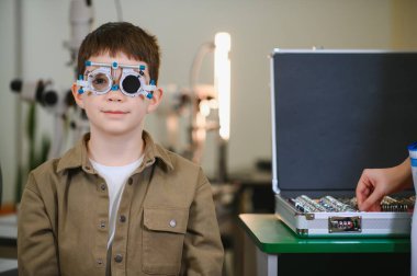 Oftalmolog, klinikte muayene sırasında küçük bir çocuğun duruşma çerçevesiyle görme yeteneğini inceliyor.